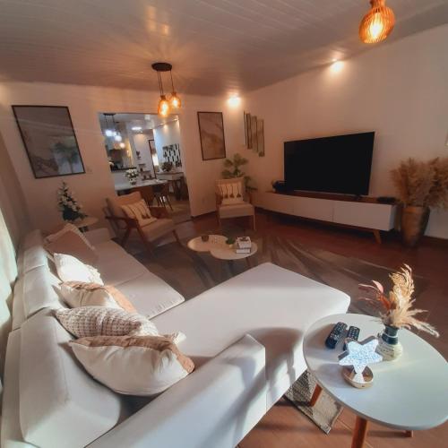 a living room with a white couch and a flat screen tv at Residência Thomas in Itacaré