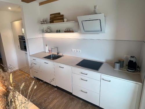 a kitchen with white cabinets and a sink at Landhaus Jarnitz in Ralswiek