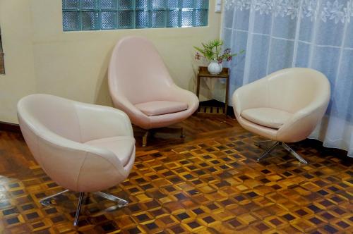 two white chairs sitting in a living room at Excellentia Antsirabe in Antsirabe