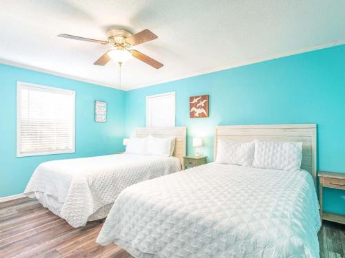 two beds in a bedroom with blue walls and a ceiling fan at Toes in the Sand in Tybee Island
