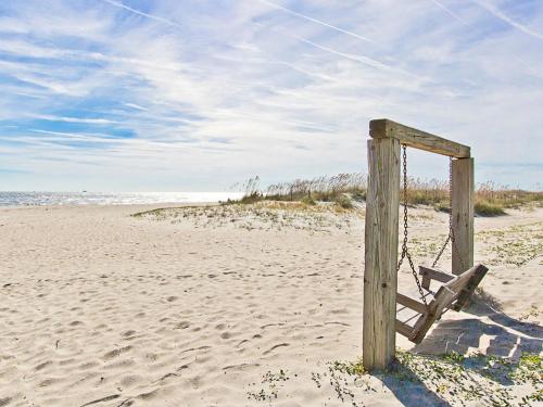 a wooden post on a sandy beach with the ocean at Toes in the Sand in Tybee Island