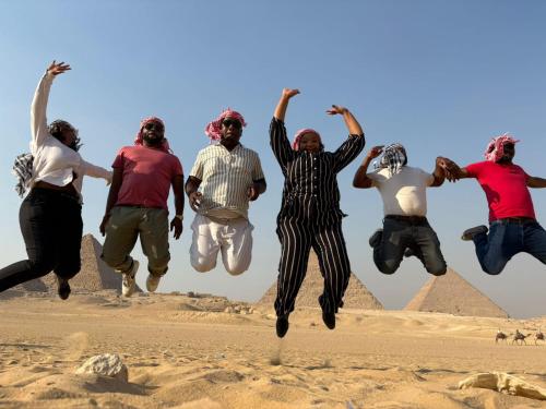 a group of people jumping in the air in front of the pyramids at sphinx one centre hotel in Banī Ghālib
