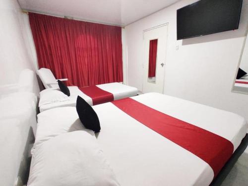 two beds in a room with a red window at Hotel Casablanca Cañaveral in Floridablanca