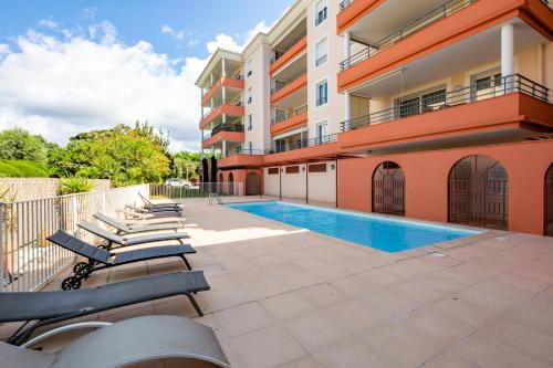 - une rangée de chaises longues à côté d'un bâtiment avec piscine dans l'établissement Résidence Le Panama - maeva Home - Appartement avec terrasse 3 pièces 6 personnes - Exclusive - super Home MAE-1023, à Fréjus