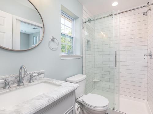 a white bathroom with a toilet and a mirror at The Flying Pigs Cottage in Tybee Island