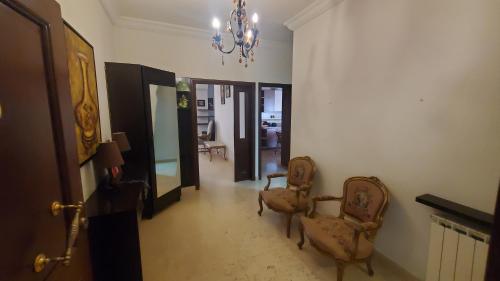 a hallway with two chairs and a chandelier at Apartment 201 in Al Ghuwayyāt