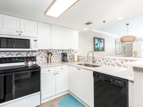 a kitchen with white cabinets and black appliances at Summer Winds 528 in Tybee Island