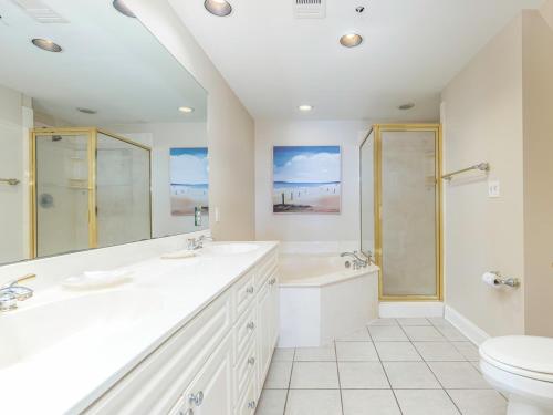 La salle de bains blanche est pourvue de 2 lavabos et de toilettes. dans l'établissement Sandpiper 205, à Tybee Island