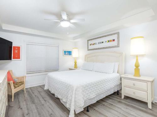 une chambre blanche avec un lit et un ventilateur de plafond dans l'établissement Ocean Song 333, à Tybee Island