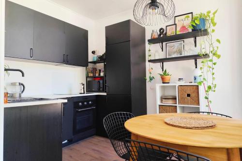 une cuisine avec des armoires noires et une table en bois dans l'établissement Bright 45m near the Jardin Public, à Bordeaux
