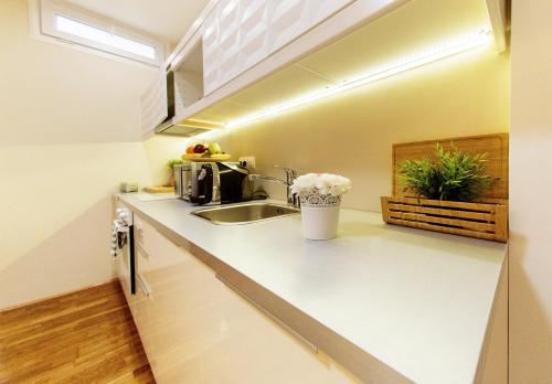 a kitchen with white counters and a sink at La Pergola & Prestige Panzió in Kaposvár