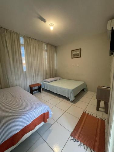 a bedroom with two beds and a tv in it at UDI Hostel Hospedaria in Uberlândia