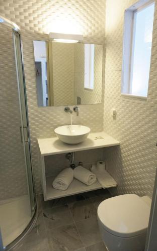 a bathroom with a sink and a toilet and a mirror at Polos Hotel Paros in Parikia