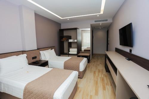 a hotel room with two beds and a flat screen tv at Joelle Premium Hotel in Sarandë
