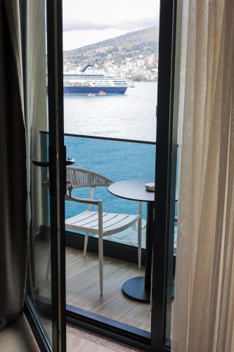 a balcony with a table and a ship in the water at Joelle Premium Hotel in Sarandë