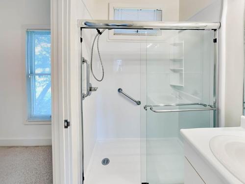 a white bathroom with a shower and a sink at Mercy Me in Tybee Island