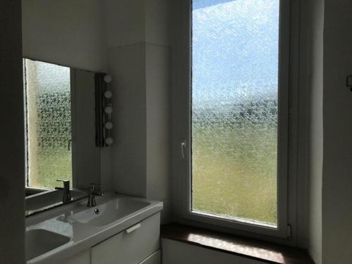 une salle de bain avec un lavabo et une grande fenêtre dans l'établissement La maison Pont Rouge, à Carcassonne