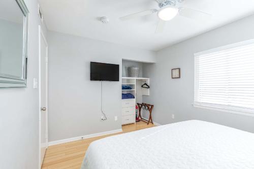 a white bedroom with a bed and a flat screen tv at Lighthouse Point 25A in Tybee Island