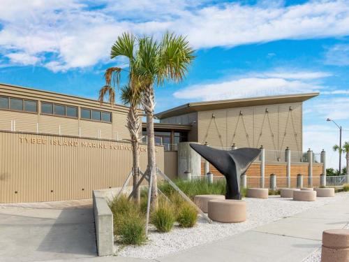 a sculpture in front of a building with a palm tree at Lighthouse Point 15C in Tybee Island