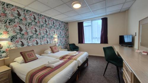a hotel room with two beds and a television at Heathlands Hotel in Bournemouth