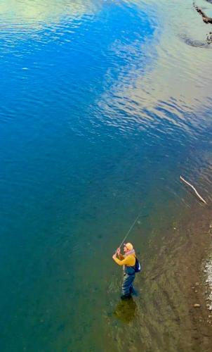 a man standing in the water holding a fishing rod at Cabañas Leufü Lodge con Tinaja in Valdivia