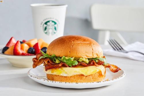 a chicken sandwich on a plate with a bowl of fruit at Courtyard by Marriott Indianapolis Fishers in Fishers