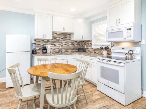 a kitchen with white cabinets and a wooden table and chairs at Dune B in Tybee Island