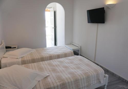a room with two beds and a tv on the wall at Polos Hotel Paros in Parikia