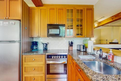 a kitchen with wooden cabinets and a sink and a refrigerator at Stowe Mountain Road Escape in Stowe