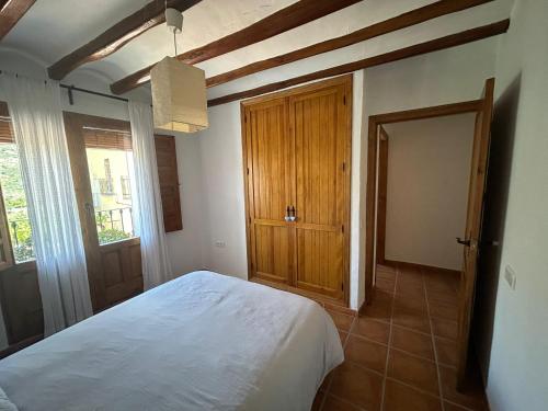 a bedroom with a white bed and a wooden door at casa los almendros in Confrides