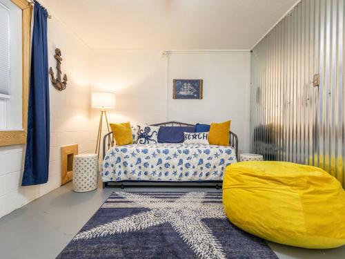 a bedroom with a bed and a yellow ottoman at Castaway Cottage in Tybee Island