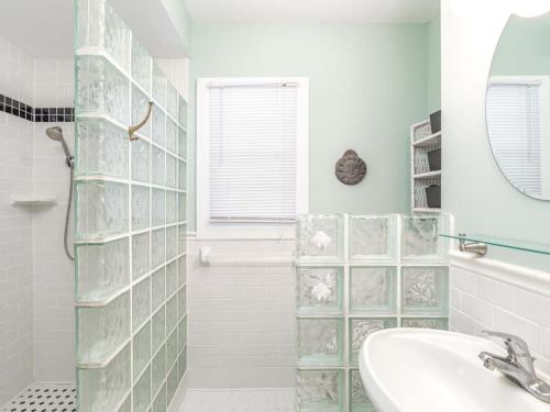 a white bathroom with a sink and a mirror at Caretta Cottage in Tybee Island