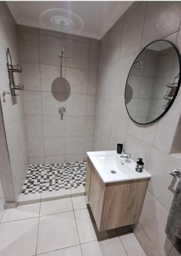 ein Badezimmer mit Dusche, Waschbecken und Spiegel in der Unterkunft Sweetpea in Boksburg