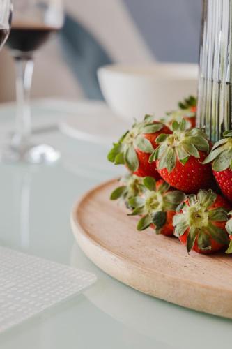 a plate of strawberries on a table with a glass of wine at Fl9 Thelodge-sea View W Huge Terrace By Homely in Mellieħa
