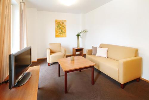 a living room with a couch and a tv and a table at Gästehaus am Schloss in Schwebheim