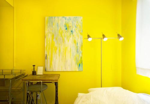 a yellow bedroom with a table and a painting at Apartment Hotel Shinjuku in Tokyo