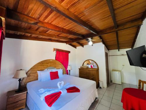 a bedroom with a large white bed with red bows at Hotel Villas del Valle in Valle de Ángeles
