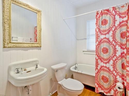 Un baño con inodoro, lavabo y espejo. en Bikini Top, en Tybee Island