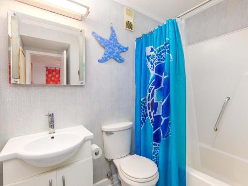 a bathroom with a toilet sink and a blue shower curtain at Beach Racquet A330 in Tybee Island