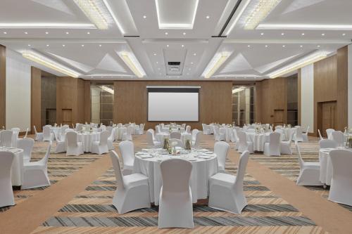 a conference room with white tables and chairs and a projection screen at Holiday Inn Tabuk by IHG in Tabuk