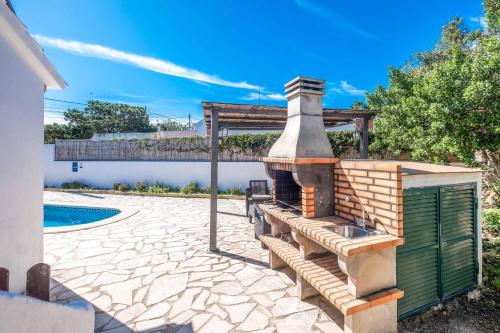 a patio with an outdoor oven next to a pool at Villa Chiquita in Cala'n Porter