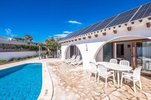 a patio with a table and chairs next to a pool at Villa Chiquita in Cala'n Porter