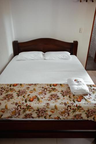 a bed with a floral bedspread and two towels on it at Hotel Agroturistico Palma Vino in Arboletes