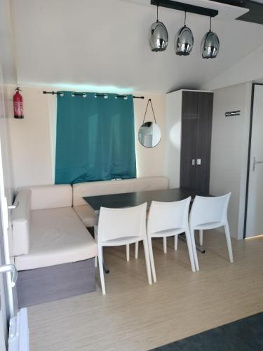 une salle à manger avec une table et des chaises blanches dans l'établissement Mobile home, à Vic-la-Gardiole