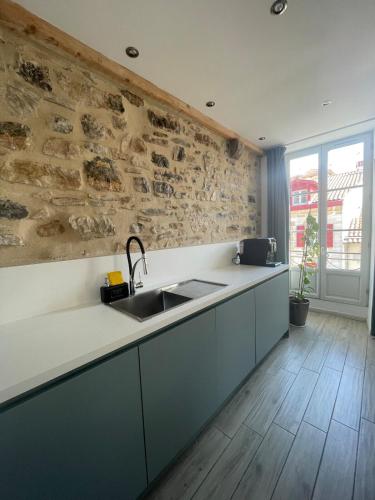 une cuisine avec un évier et un mur en pierre dans l'établissement Bel appartement lumineux au cœur de Bayonne, à Bayonne