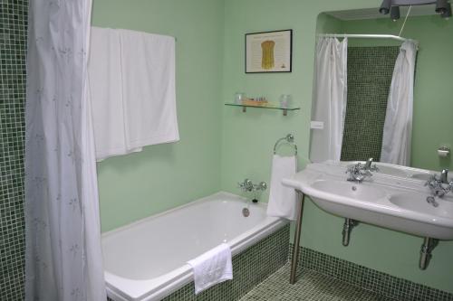 uma casa de banho com uma banheira e um lavatório e uma banheira em Posada Real del Pinar em Pozal de Gallinas