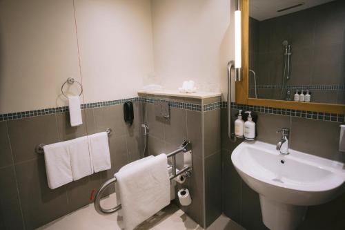a bathroom with a sink and a toilet and a mirror at Holiday Inn Abu Dhabi by IHG in Abu Dhabi