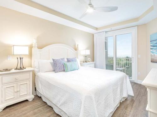 a white bedroom with a white bed and a window at Beach House 413 in Tybee Island