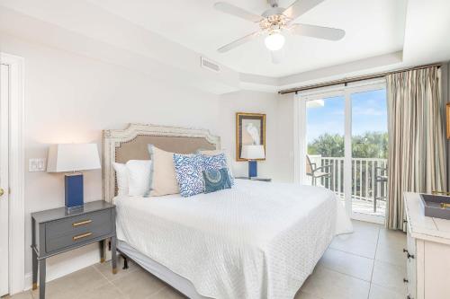 a white bedroom with a bed and a balcony at Beach House 415 in Tybee Island
