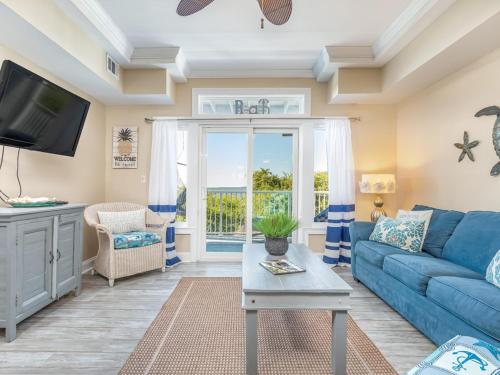 a living room with a blue couch and a tv at Bay View Villas 107 in Tybee Island